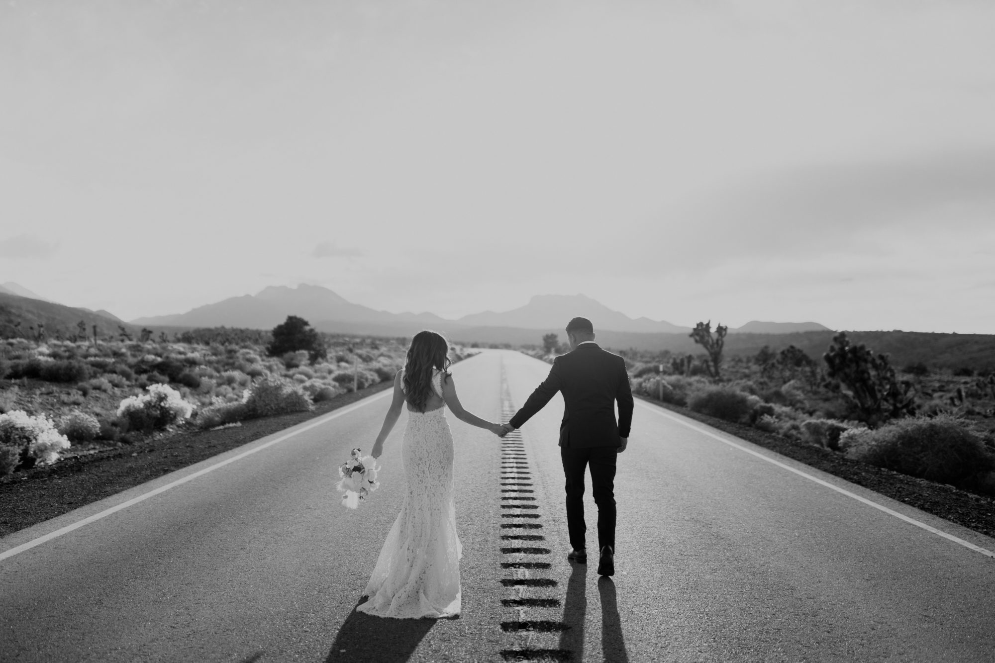 Couple posing on vacant road in the desert during adventure elopement session 