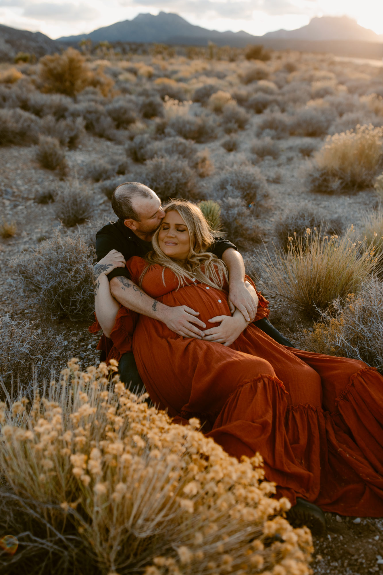 Couple during desert photoshoot laying down and cuddling
