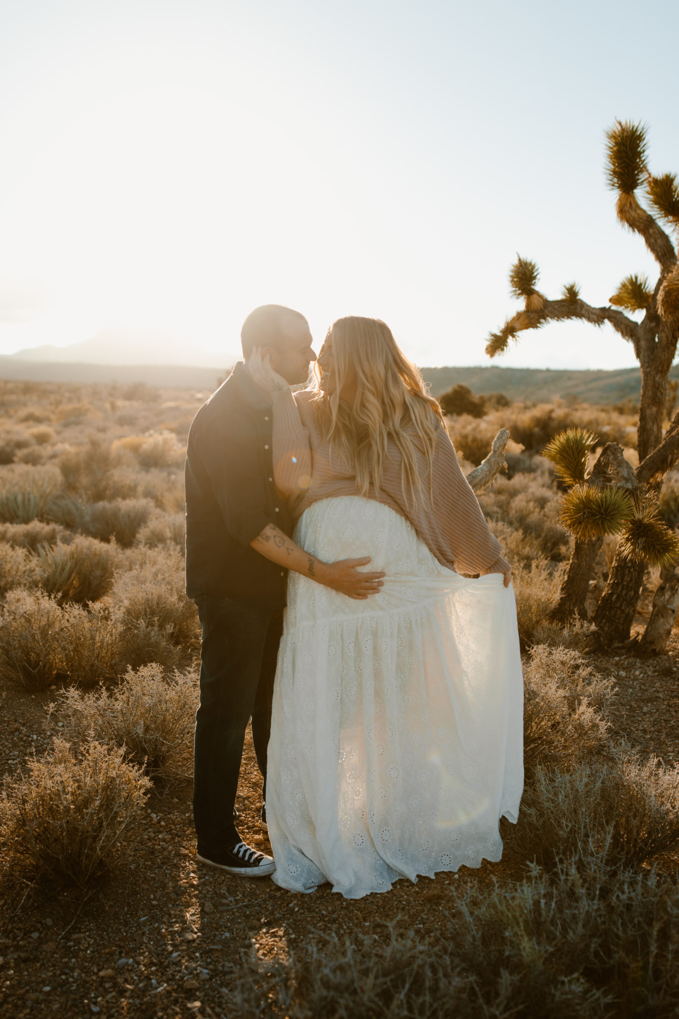 Man holding womans belly during desert maternity session