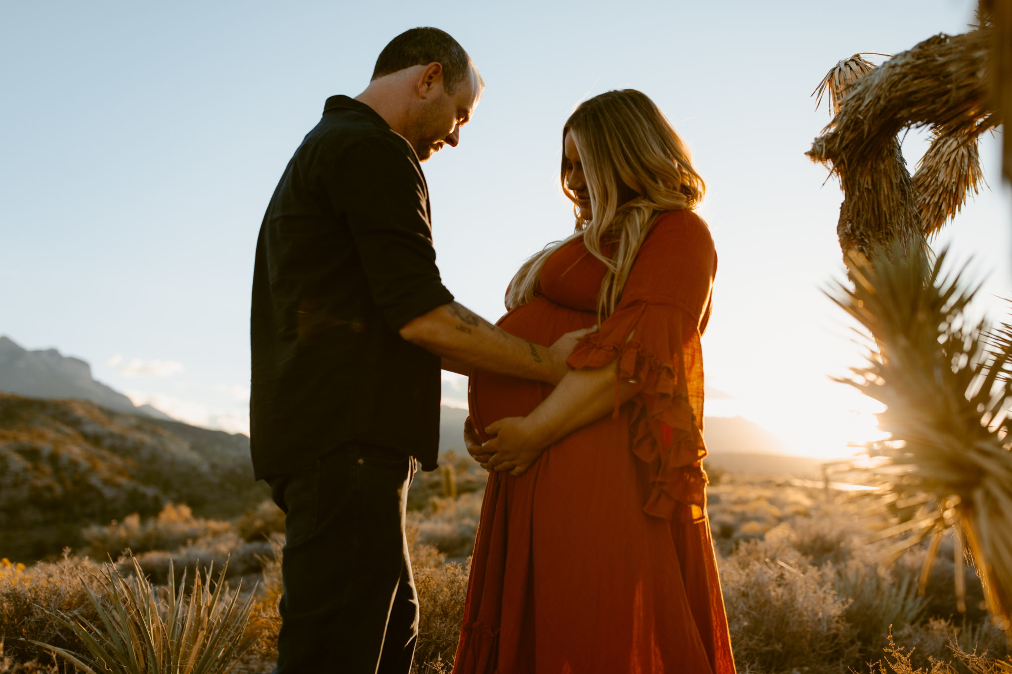 Man and woman posing for maternity session in the desert 