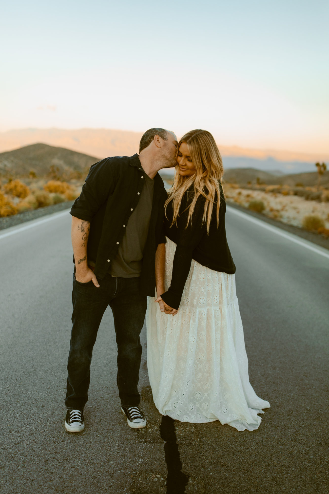 Man and woman posing in road for desert photoshoot 