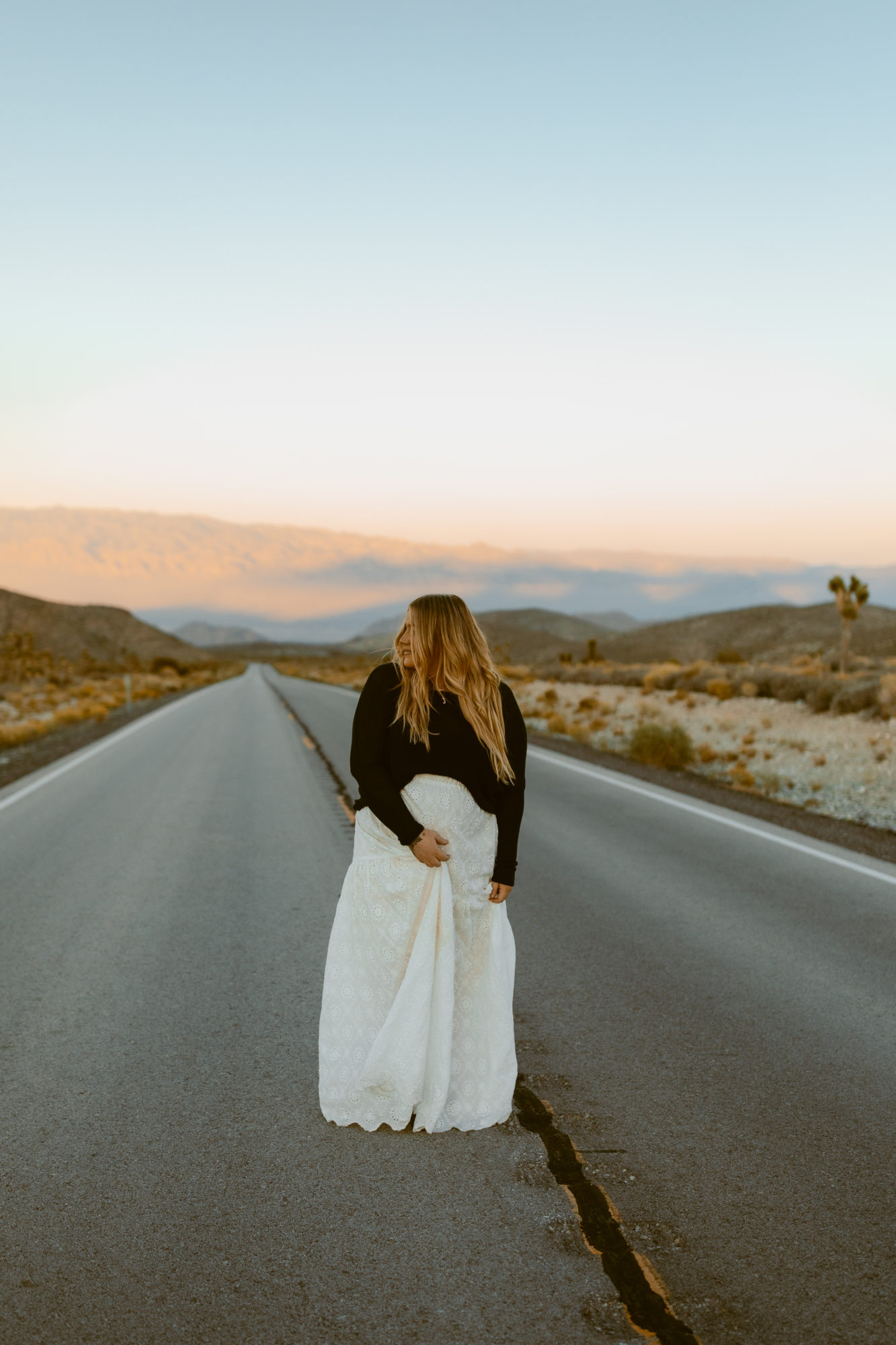 Woman posing in the middle of the road for desert photoshoot 